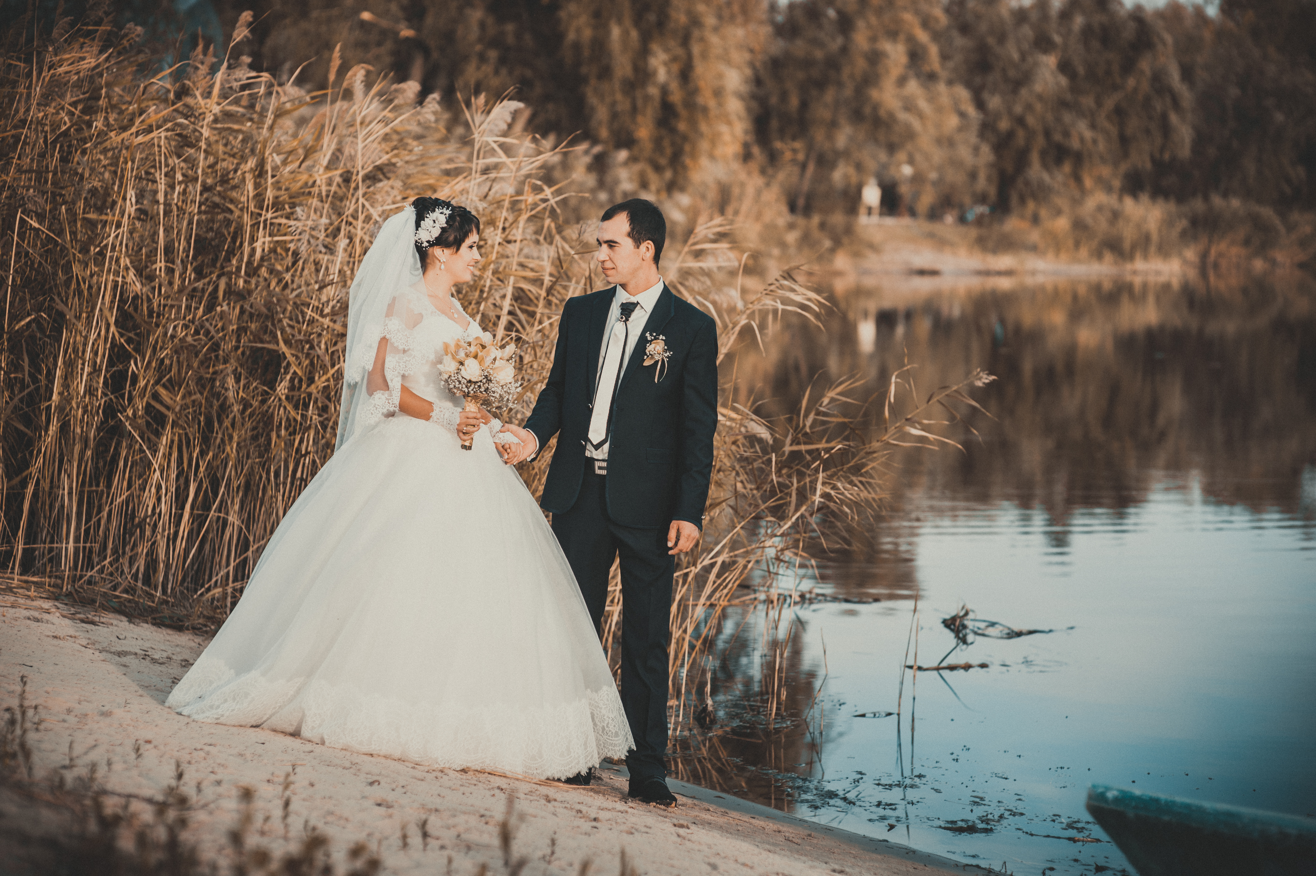 wedding: bride and groom on the seashore. Honeymoon. The bride and groom hugging on the shore of Lake. groom and bride hugging on a green lake. Groom and Bride in a park. wedding dress. Bridal wedding bouquet of flowers